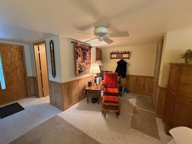 living area featuring ceiling fan and wooden walls