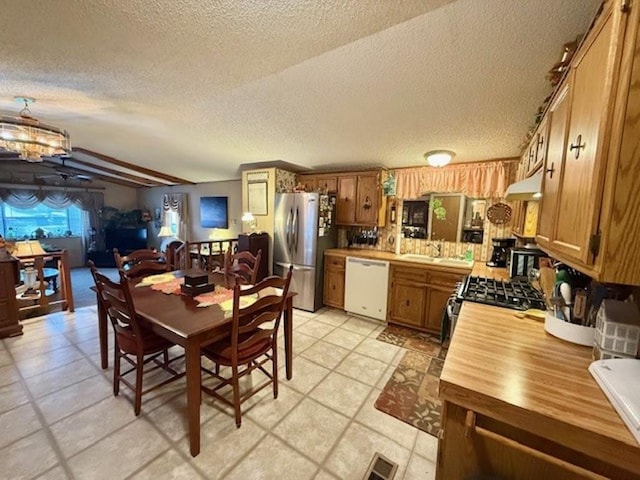 kitchen with appliances with stainless steel finishes, custom range hood, a textured ceiling, sink, and a chandelier