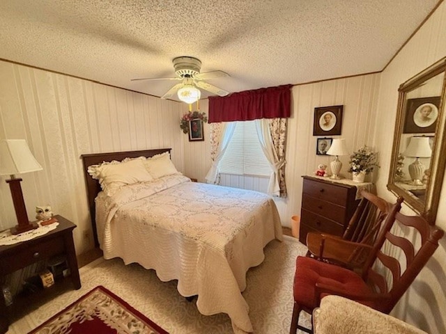 carpeted bedroom with ceiling fan, wood walls, and a textured ceiling