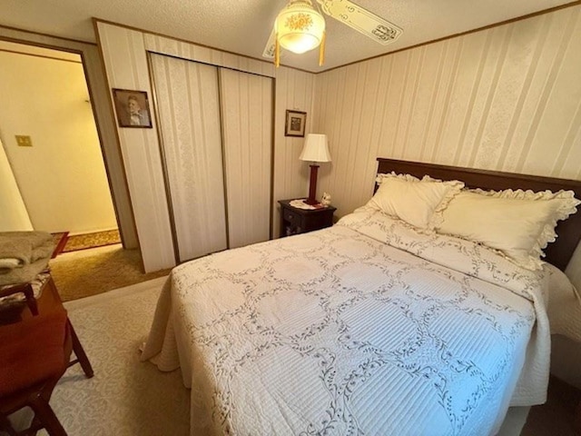 bedroom with ceiling fan, carpet floors, and a textured ceiling