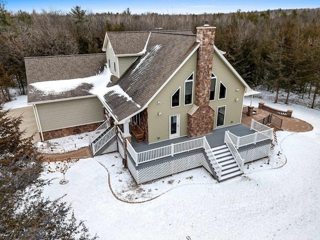 snow covered back of property with a deck