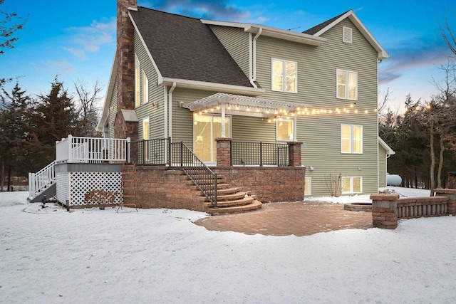 snow covered back of property with a pergola