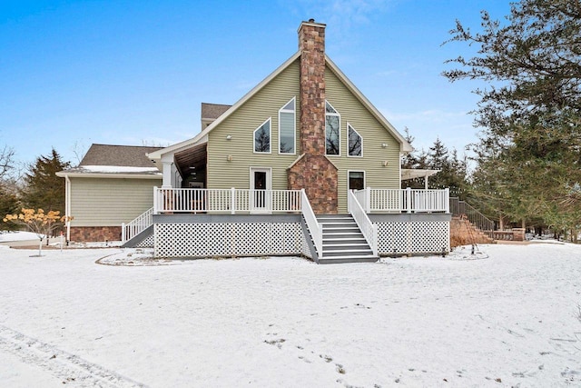 snow covered back of property featuring a deck