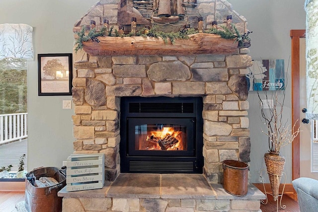 details with wood-type flooring and a stone fireplace