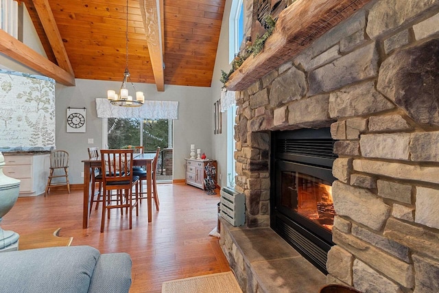 dining area with a fireplace, vaulted ceiling with beams, hardwood / wood-style flooring, and an inviting chandelier