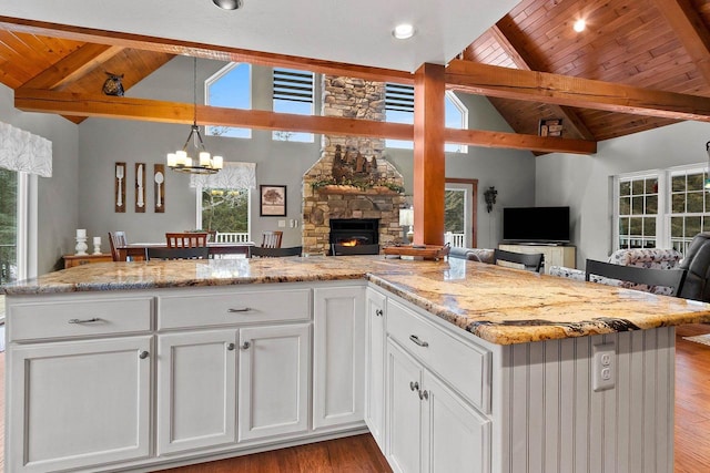 kitchen with a stone fireplace, white cabinets, and a healthy amount of sunlight