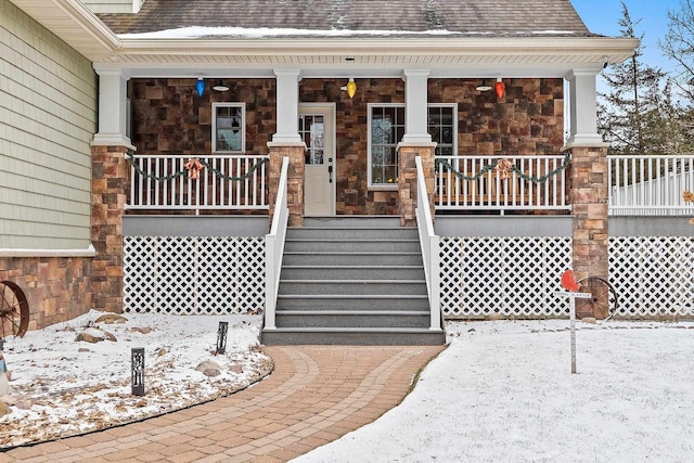 snow covered property entrance with covered porch