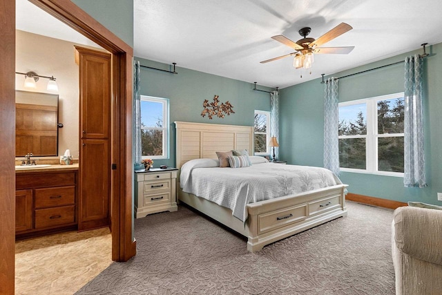 bedroom with ceiling fan, sink, light carpet, and multiple windows