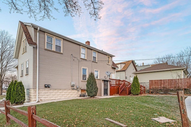 rear view of property featuring a lawn and a deck