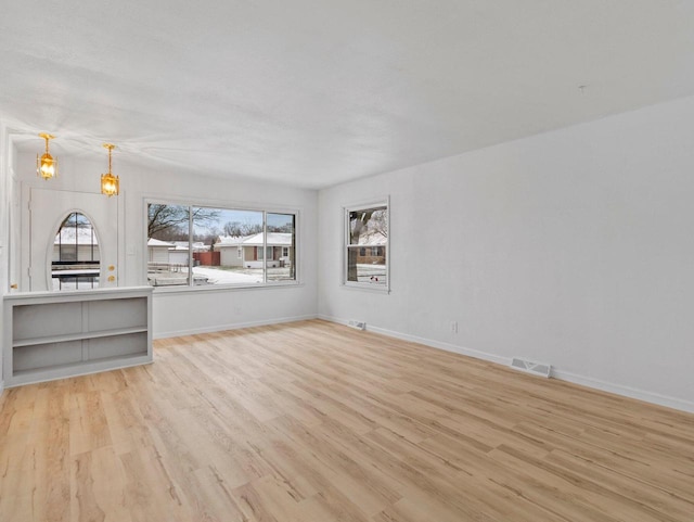 unfurnished living room with a chandelier and light hardwood / wood-style floors