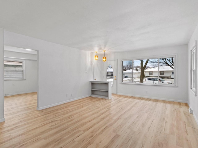 unfurnished living room featuring an inviting chandelier and light hardwood / wood-style flooring