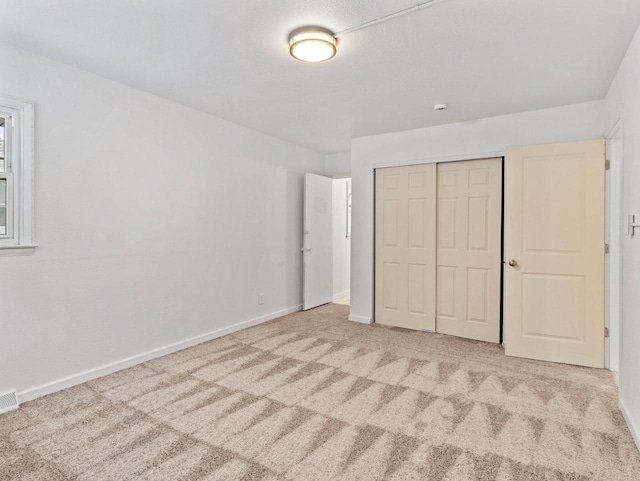 unfurnished bedroom featuring light carpet and a closet