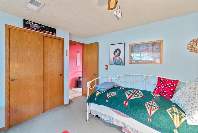 carpeted bedroom with a textured ceiling and a closet