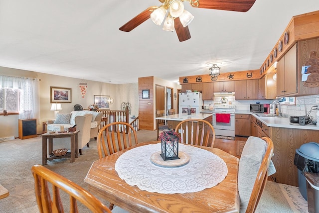 dining space featuring light carpet, sink, and ceiling fan