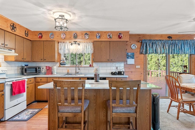 kitchen featuring sink, a center island, white range, backsplash, and light hardwood / wood-style floors