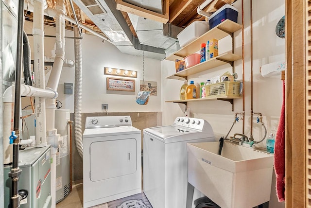 laundry room with washing machine and dryer, gas water heater, and sink