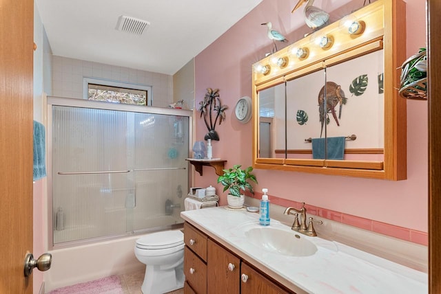 full bathroom featuring tile patterned floors, shower / bath combination with glass door, vanity, and toilet