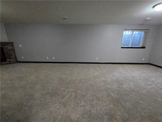 carpeted spare room with a textured ceiling and a brick fireplace