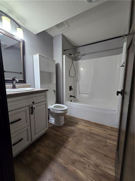 full bathroom with tub / shower combination, vanity, a textured ceiling, hardwood / wood-style floors, and toilet