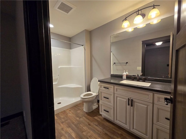 bathroom with hardwood / wood-style floors, vanity, toilet, and walk in shower