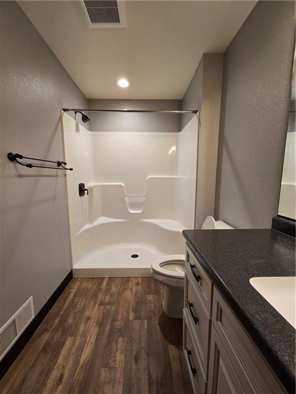 bathroom with vanity, toilet, wood-type flooring, and walk in shower