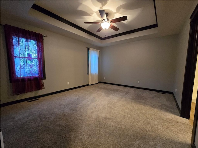 carpeted spare room with a tray ceiling and ceiling fan