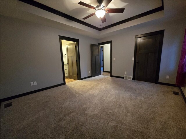 unfurnished bedroom with light colored carpet, a raised ceiling, ceiling fan, crown molding, and connected bathroom