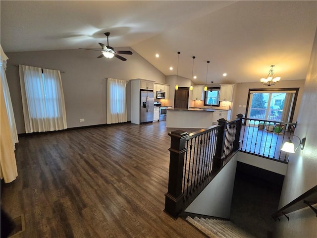 interior space featuring ceiling fan with notable chandelier, dark hardwood / wood-style flooring, and lofted ceiling