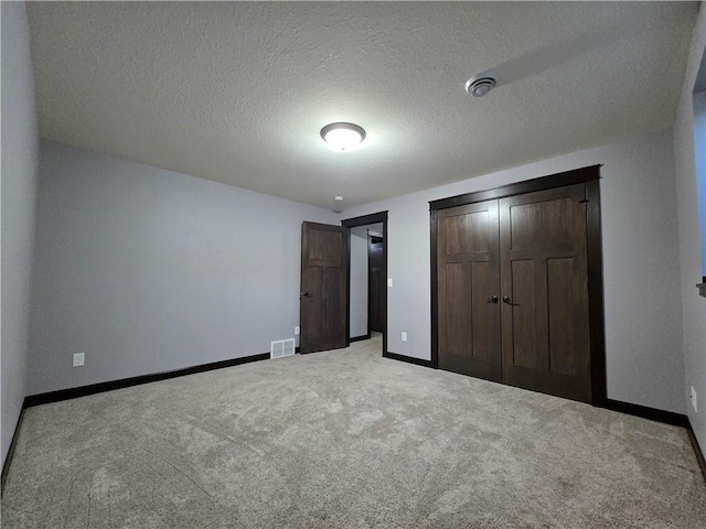 unfurnished bedroom with a closet, carpet floors, and a textured ceiling