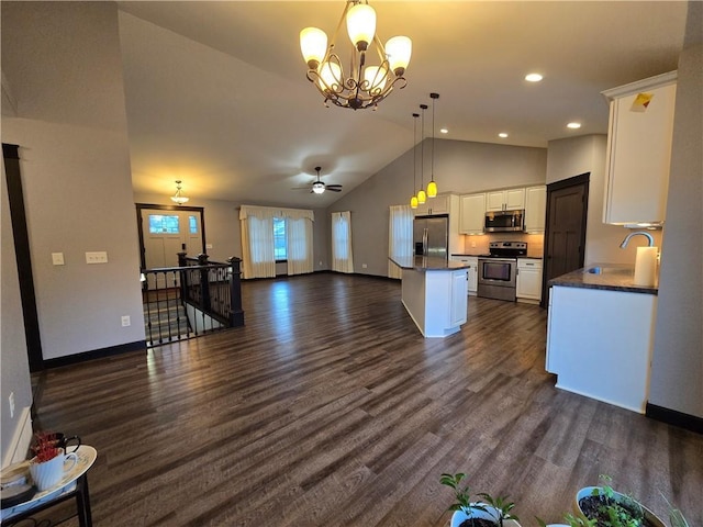 kitchen with dark wood-type flooring, pendant lighting, white cabinets, ceiling fan with notable chandelier, and appliances with stainless steel finishes