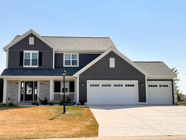 view of front of property featuring covered porch, a garage, and a front lawn