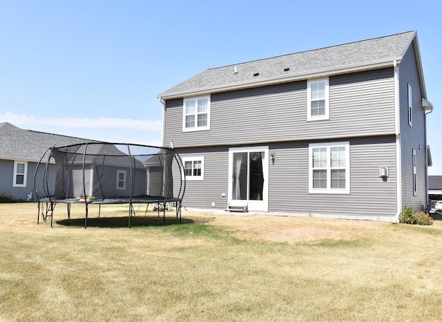 back of property featuring a yard and a trampoline