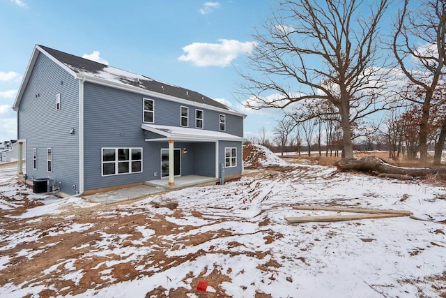 snow covered back of property featuring central AC