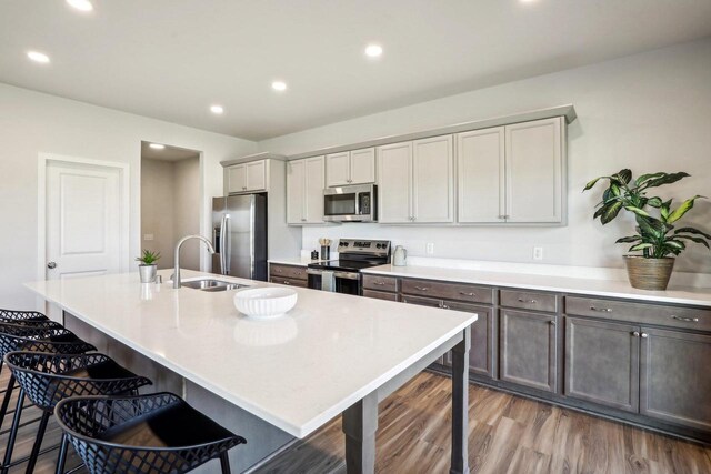 kitchen featuring an island with sink, appliances with stainless steel finishes, sink, and a kitchen bar