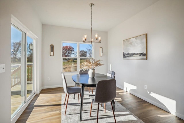 dining space with dark hardwood / wood-style flooring, plenty of natural light, and a chandelier