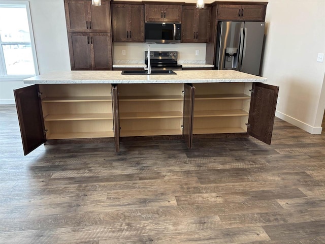 kitchen with appliances with stainless steel finishes, sink, a kitchen island with sink, and dark brown cabinets