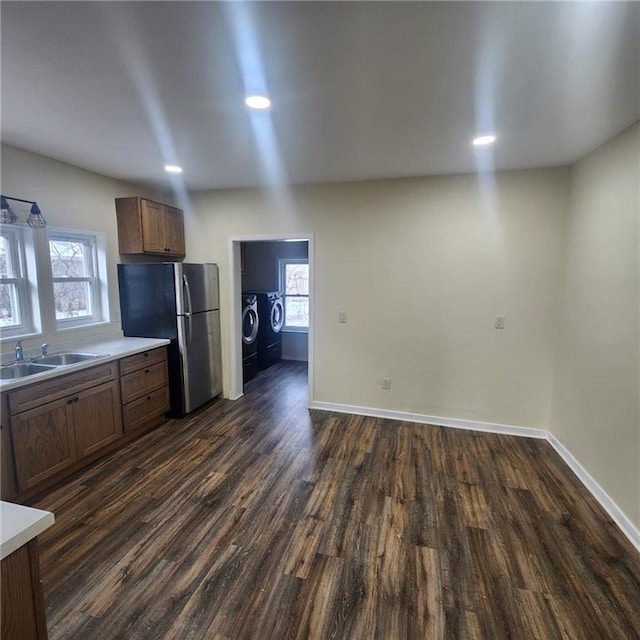 kitchen with stainless steel fridge, independent washer and dryer, dark wood-type flooring, and sink