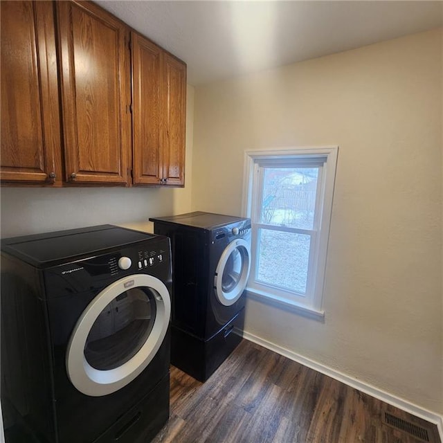 clothes washing area featuring cabinets, dark hardwood / wood-style floors, and washing machine and dryer