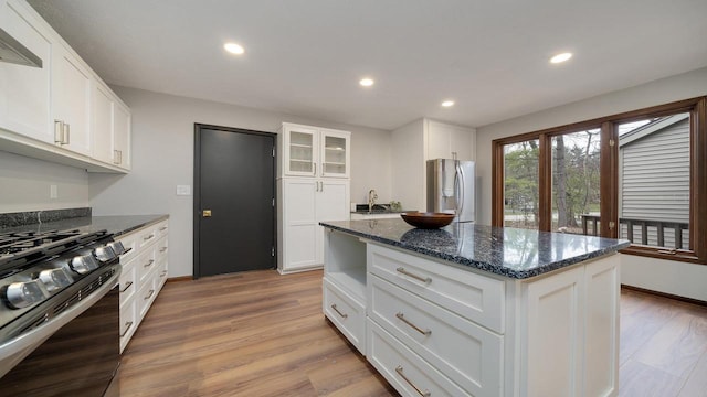 kitchen with black gas range, white cabinetry, light hardwood / wood-style floors, and stainless steel refrigerator with ice dispenser