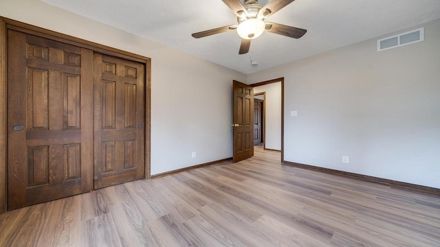 unfurnished bedroom featuring ceiling fan, light wood-type flooring, and a closet