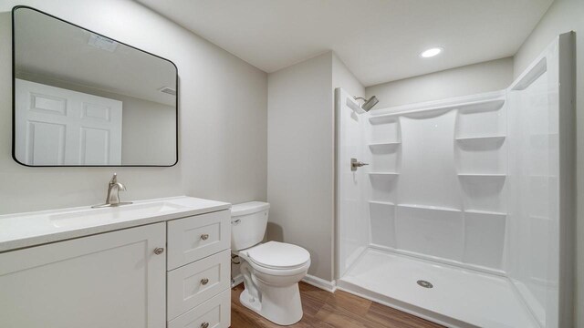 bathroom with toilet, hardwood / wood-style floors, vanity, and walk in shower