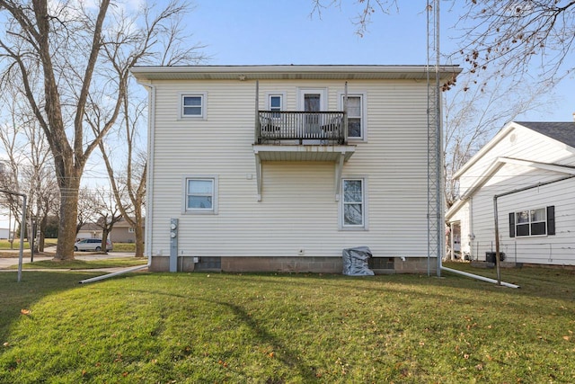 back of property with a yard and a balcony