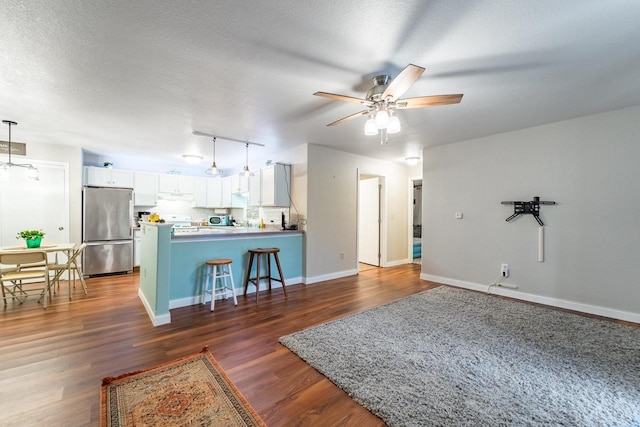 living room with a textured ceiling, dark hardwood / wood-style floors, and ceiling fan