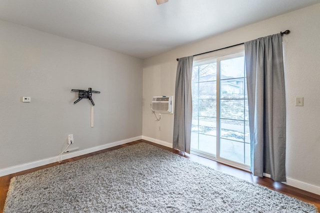 empty room with a wall unit AC and dark wood-type flooring