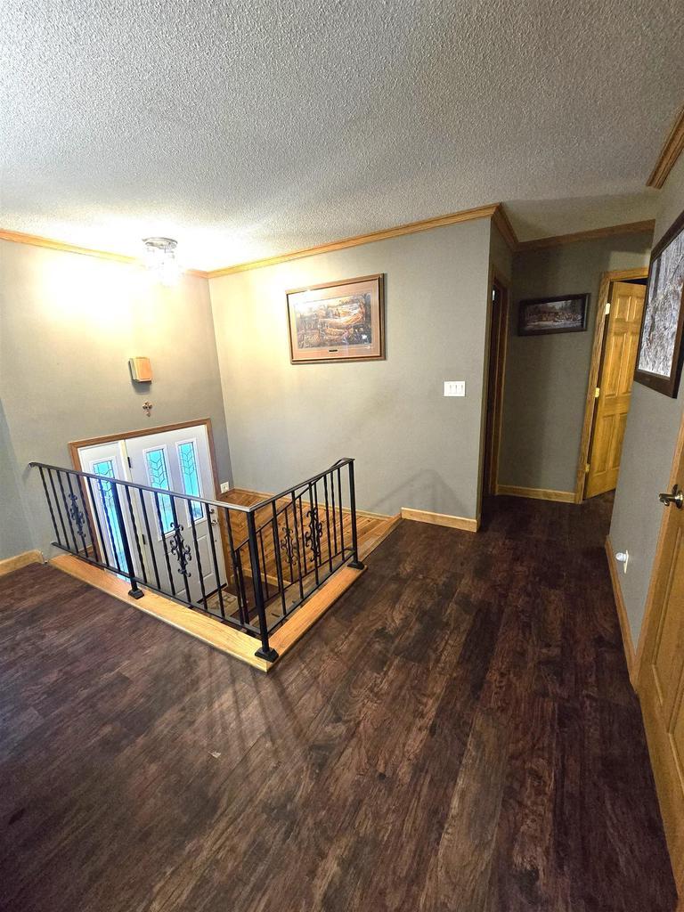 hall featuring a textured ceiling, dark hardwood / wood-style floors, and crown molding