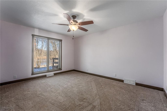 carpeted spare room with a textured ceiling and ceiling fan