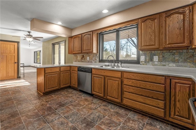 kitchen with ceiling fan, sink, stainless steel dishwasher, kitchen peninsula, and decorative backsplash