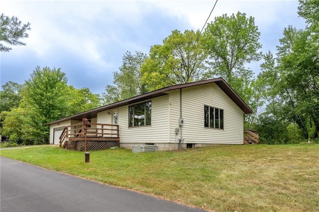 view of home's exterior featuring a lawn, a garage, and a deck