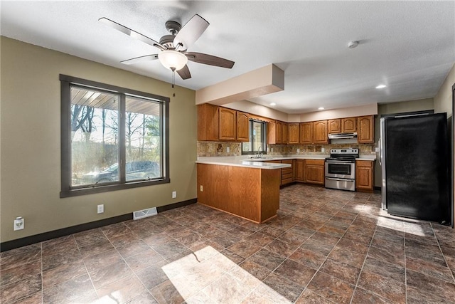 kitchen featuring ceiling fan, sink, stainless steel appliances, tasteful backsplash, and kitchen peninsula