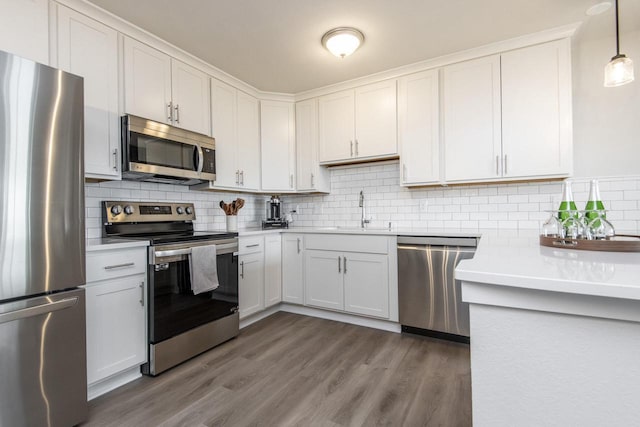 kitchen featuring white cabinets, decorative light fixtures, sink, and stainless steel appliances